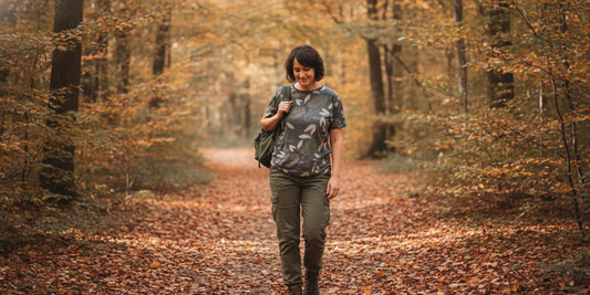 A person wearing a graphic cotton tee outdoors on a leafy trail