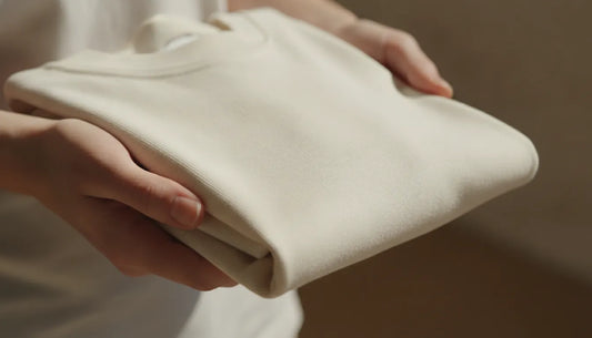 Hands holding a premium cotton t-shirt showing fabric texture and quality craftsmanship
